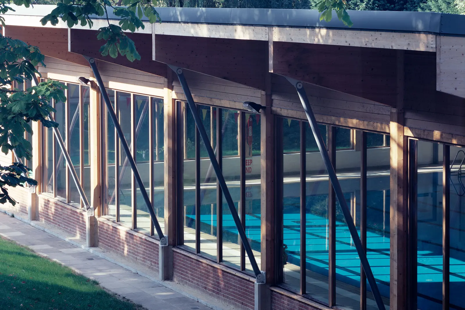 The indoor swimming pool at Mill Hill School, NW7, a timber-framed building glazed along one side, with the 25-metre pool visible inside.
